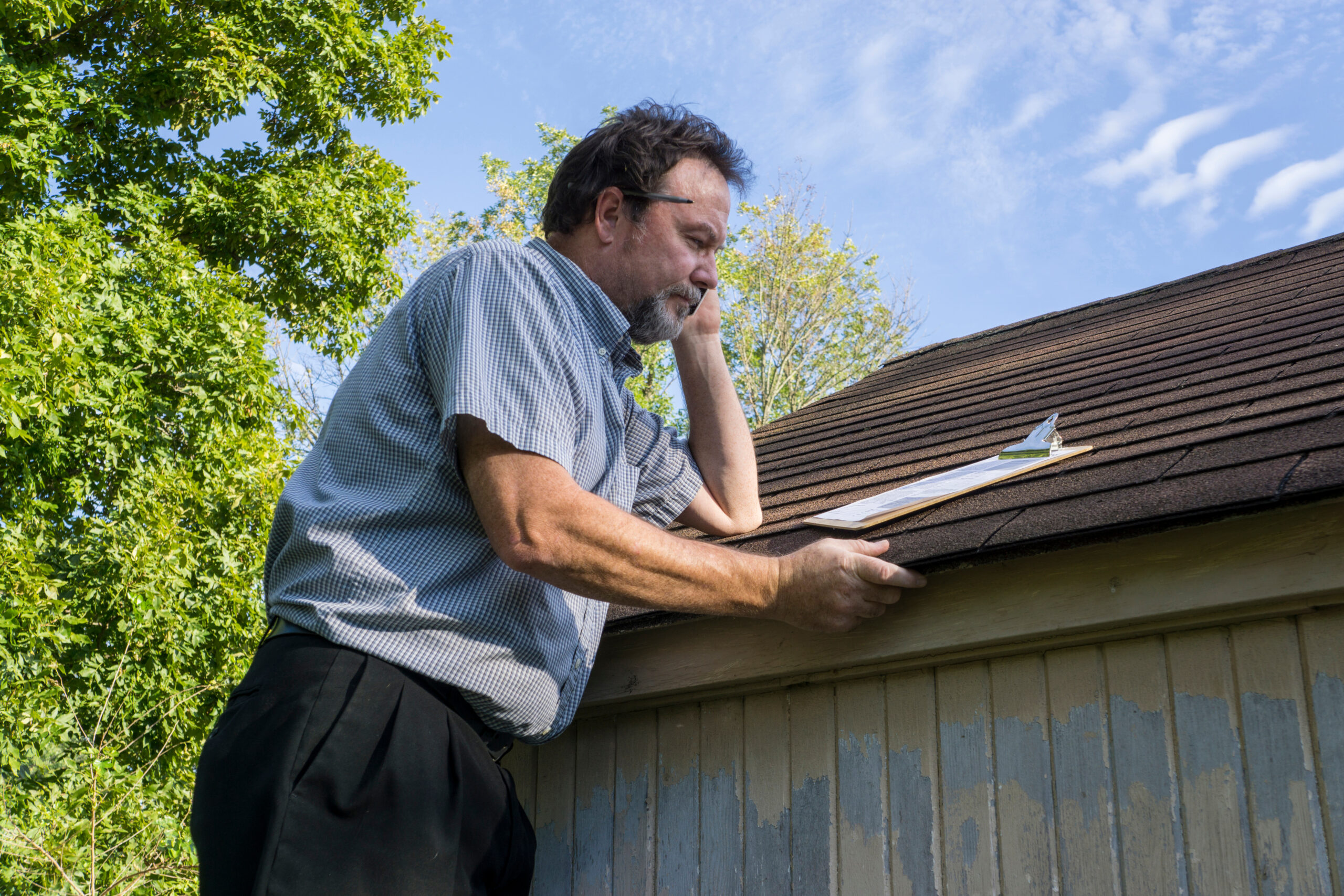 Insurance adjuster checking a insureds roof foe hail damage.